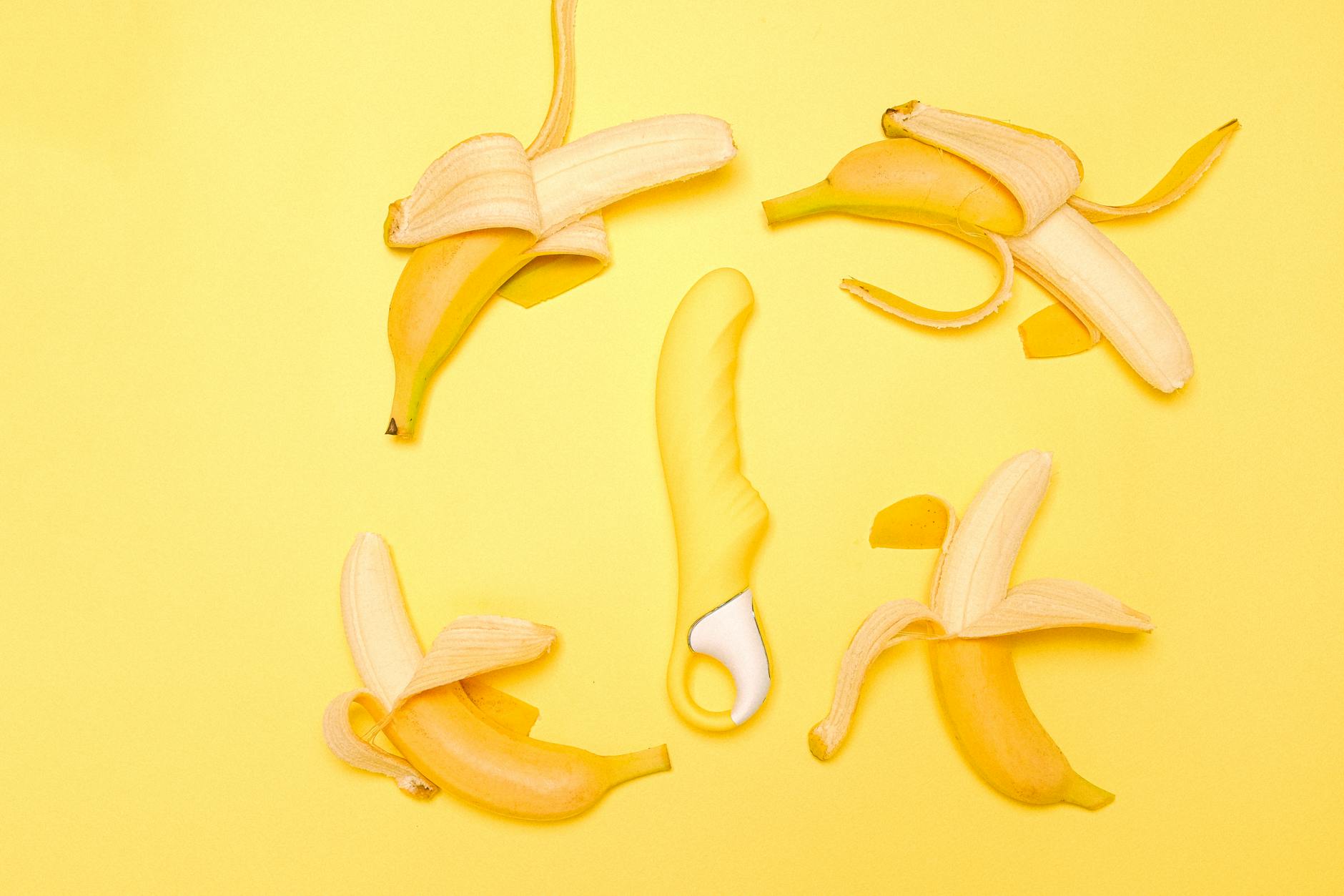Yellow lemon clitoral vibrator on a yellow background with fresh lemons